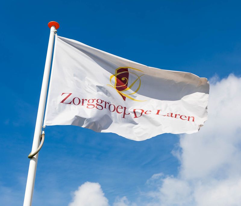 vlag Zorggroep De Laren tegen blauwe lucht